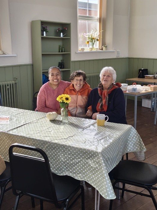 Three members of the Project St Thomas community enjoying time together around a café table